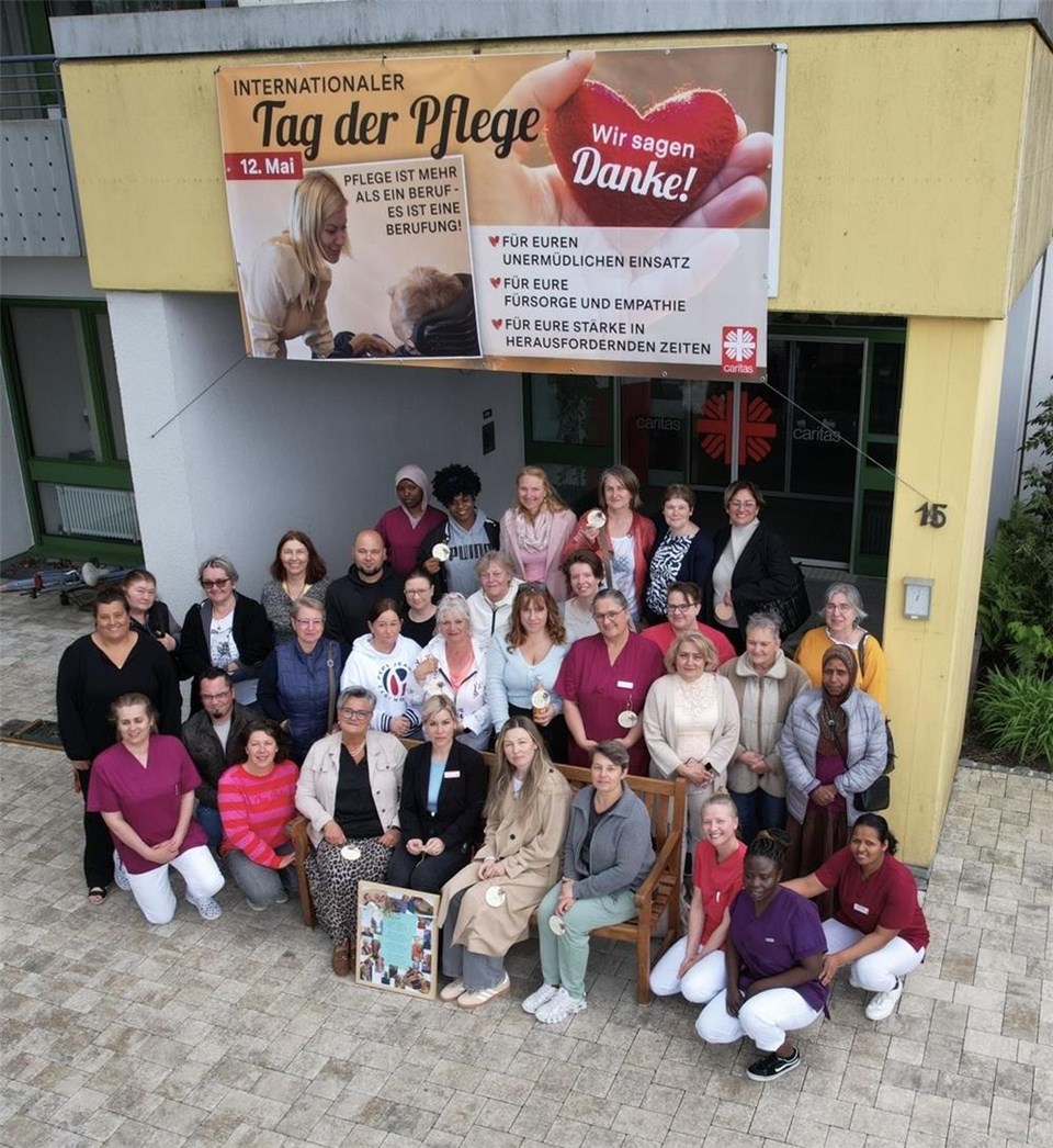 Gruppenfoto von Pflegekräften und Mitarbeitenden vor einem Gebäude unter einem Banner zum „Internationalen Tag der Pflege“. Auf dem Banner steht „Wir sagen Danke!“ und würdigt Einsatz, Fürsorge und Empathie in der Pflege.